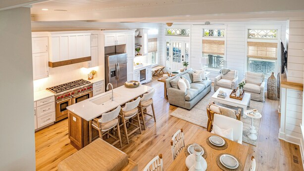 A modern kitchen with white cabinetry, a central island, and a dining area with a wooden table and chairs. - Rooftop Deck & Ocean Views—Luxury 5BR/4.5BA  Single Family, Across from Beach! (Ocean City)