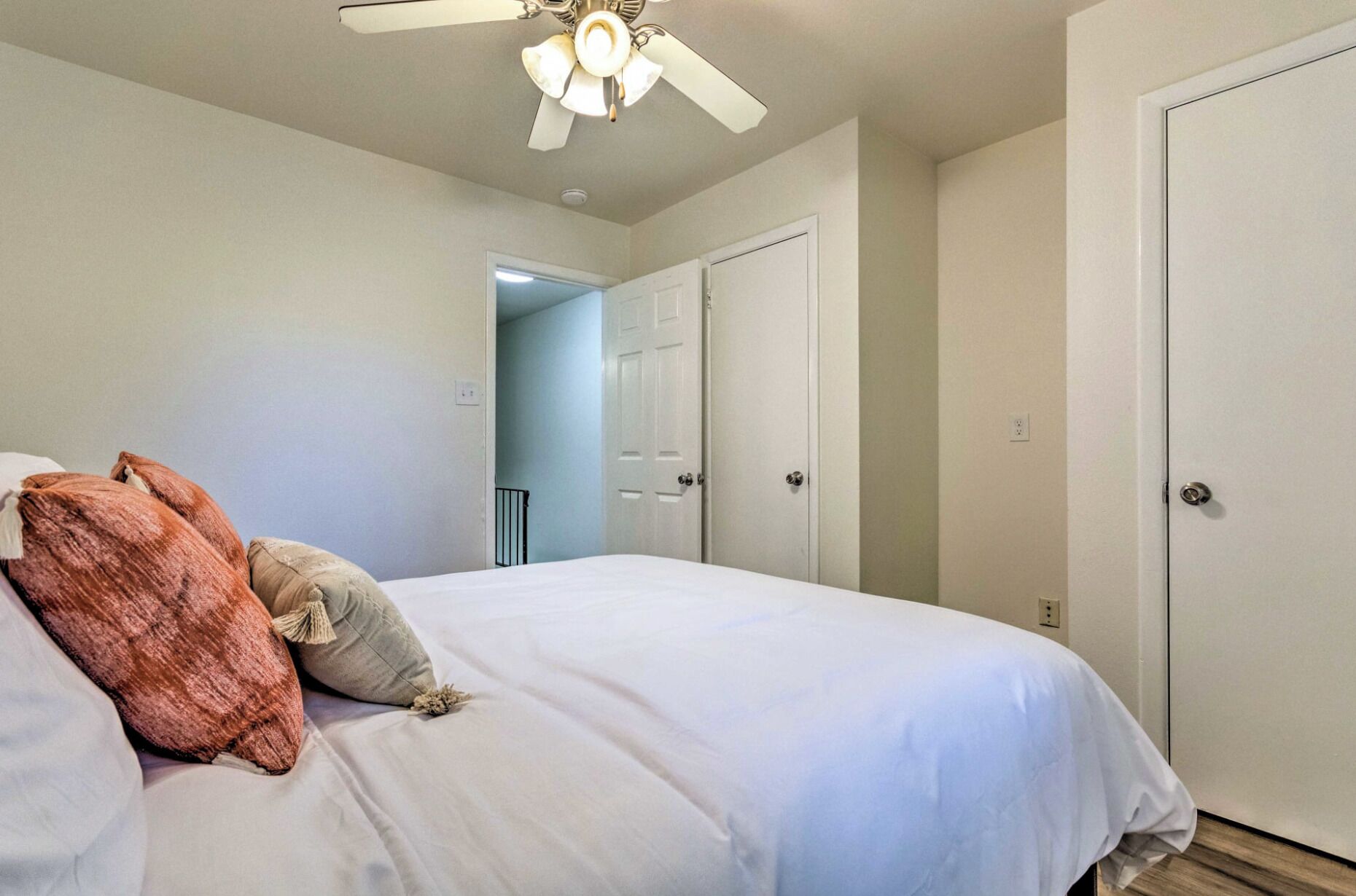 A bedroom with a bed, a ceiling fan, and two white doors.