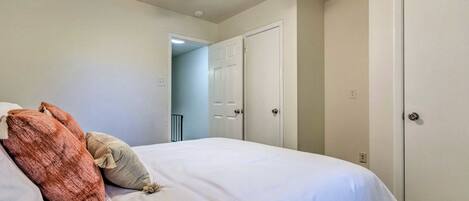 A bedroom with a bed, a ceiling fan, and two white doors.