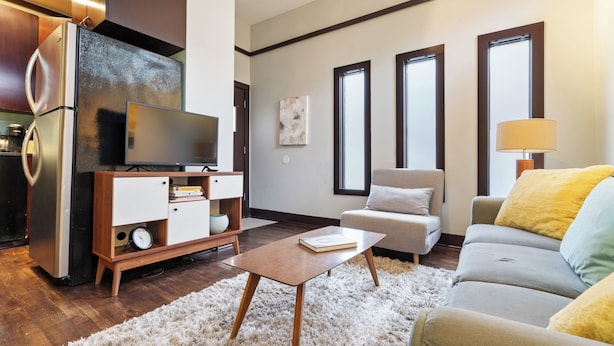 Una sala moderna con televisor de pantalla plana, una mesita de madera, un sofá y un mueble bajo.