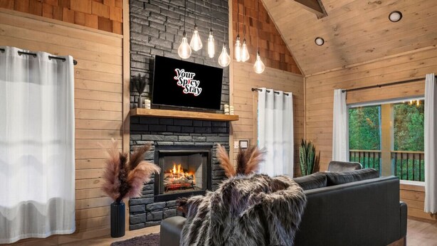 A cozy living room with a fireplace, a television mounted above it, and a sofa.