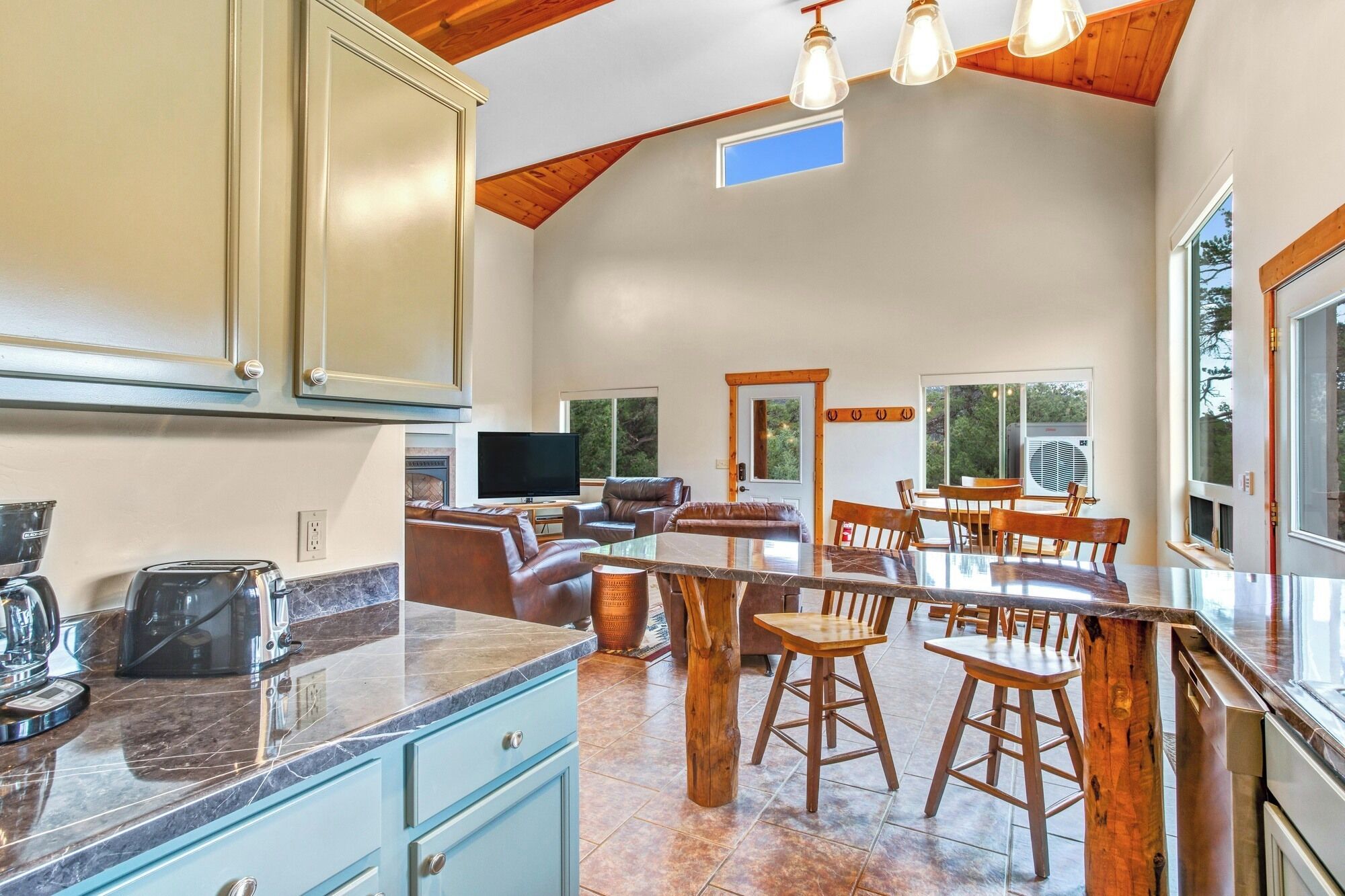 A spacious kitchen with a large island, wooden ceiling beams, and a dining area with a wooden table and chairs.