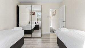Et hotelværelse med to senge, et stort spejl, en radiator og en dør til et andet rum.
