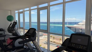 Une salle de sport équipée de matériel d’exercice et dotée d’une grande fenêtre donnant sur l’océan.