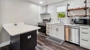 Una cocina moderna con armarios blancos, electrodomésticos de acero inoxidable y lavavajillas empotrado.