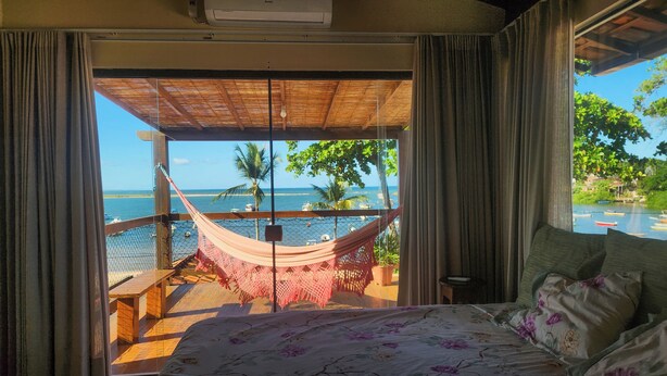 A bedroom with a view of a beach and ocean. - Casa Aberta (Itacaré)