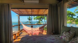 A bedroom with a view of a beach and ocean. - Casa Aberta (Itacaré)