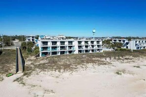 A coastal hotel with multiple floors, a prominent lighthouse, and a sandy beach area.