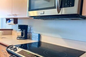 A kitchen with a microwave, an induction cooktop, and a coffee maker.