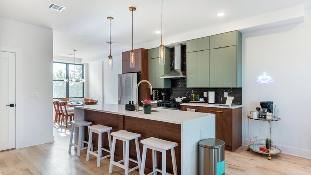 Een moderne keuken met een centraal eiland, barstoelen en hanglampen.