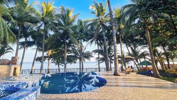 A pool area with tiled flooring and palm trees.