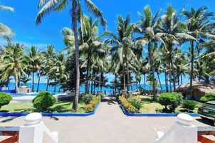 A resort pathway lined with palm trees leading to a beach.