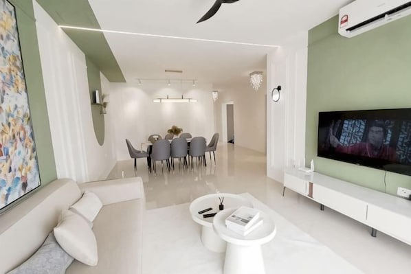 Un salon moderne doté d’un téléviseur à écran plat, d’un coin repas et d’un canapé.