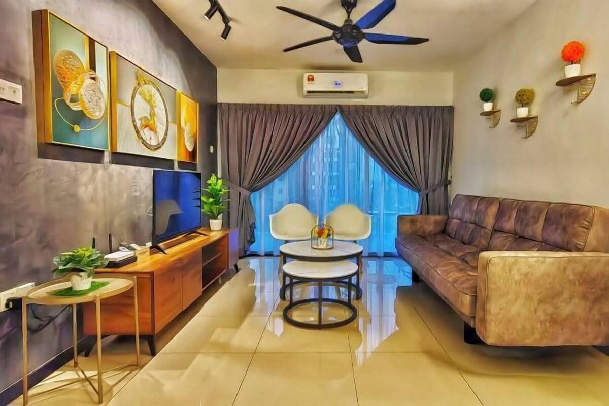 A modern living room with a sofa, a TV, a ceiling fan, and a large window with curtains.