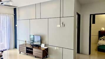 Une chambre moderne dotée d’une grande armoire, d’un téléviseur posé sur un meuble en bois et d’une porte donnant sur une autre pièce.