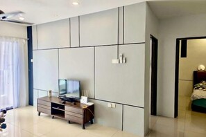 A modern room with a large wardrobe, a television on a wooden cabinet, and a door leading to another room. - Ipoh The Manhattan Suites Apartment by IWH (Ipoh)