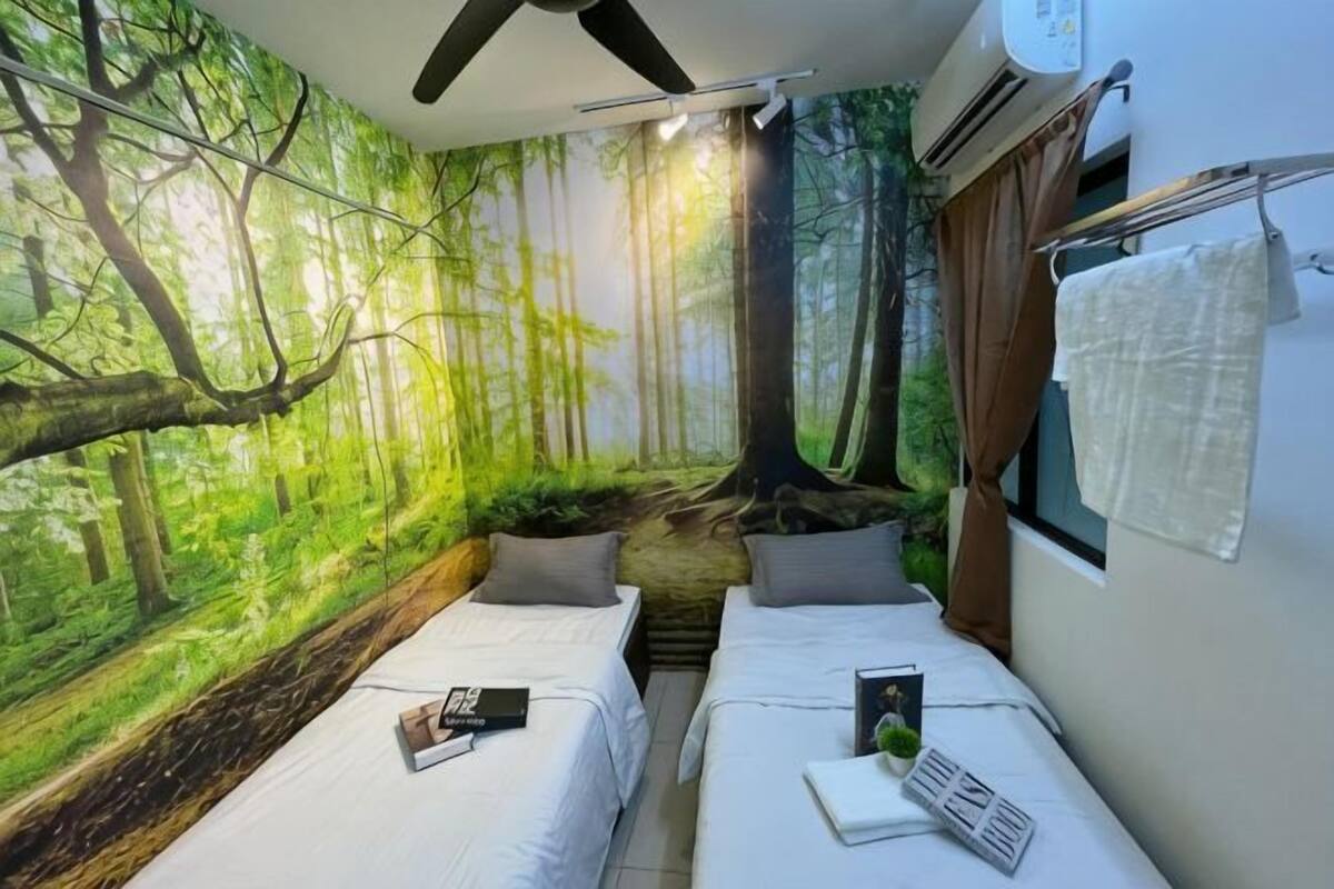 A room with two beds, a forest mural, a window with curtains, and an air conditioning unit.
