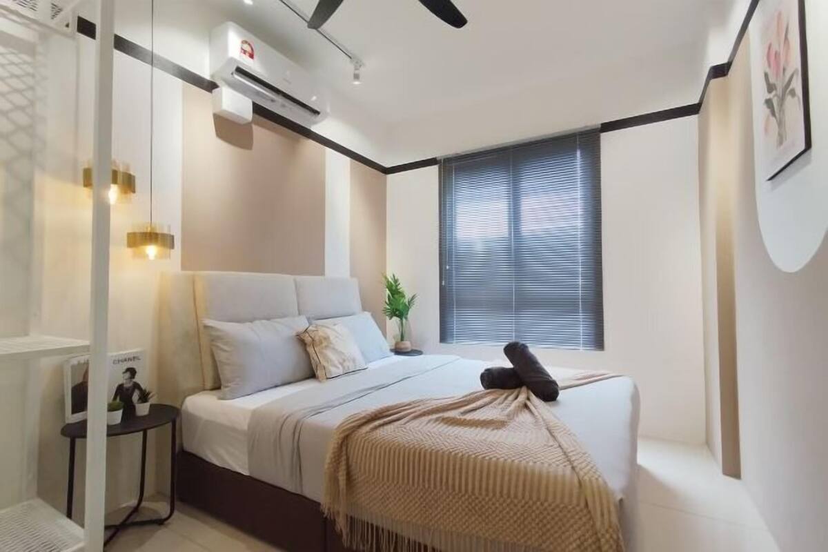 A modern bedroom with a bed, bedside table, air conditioning unit, and a window with blinds.