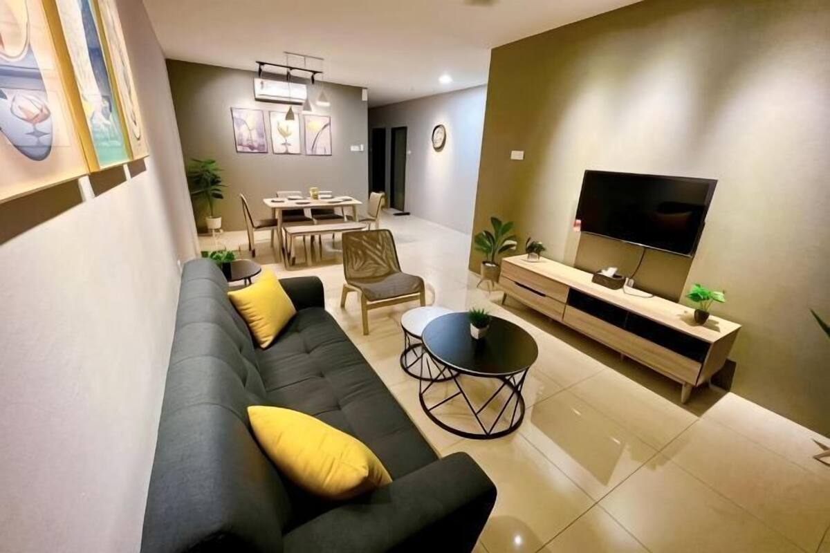 A modern living room with a sofa, TV, dining table, and chairs.
