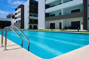 A modern building with a swimming pool, outdoor seating, and a well-maintained lawn. - Marina cerritos Torre 1 (Mazatlán)
