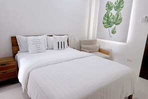 A bedroom with a bed, pillows, a chair, and a wall with a plant.