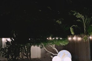 A garden area with a wooden fence, a tree, and spherical lights. - 1949 Dreamy Home (Panglao Municipality)