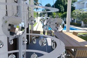 Une structure blanche à plusieurs niveaux, ornée de miroirs sphériques, avec une piscine et des meubles d’extérieur en arrière-plan.