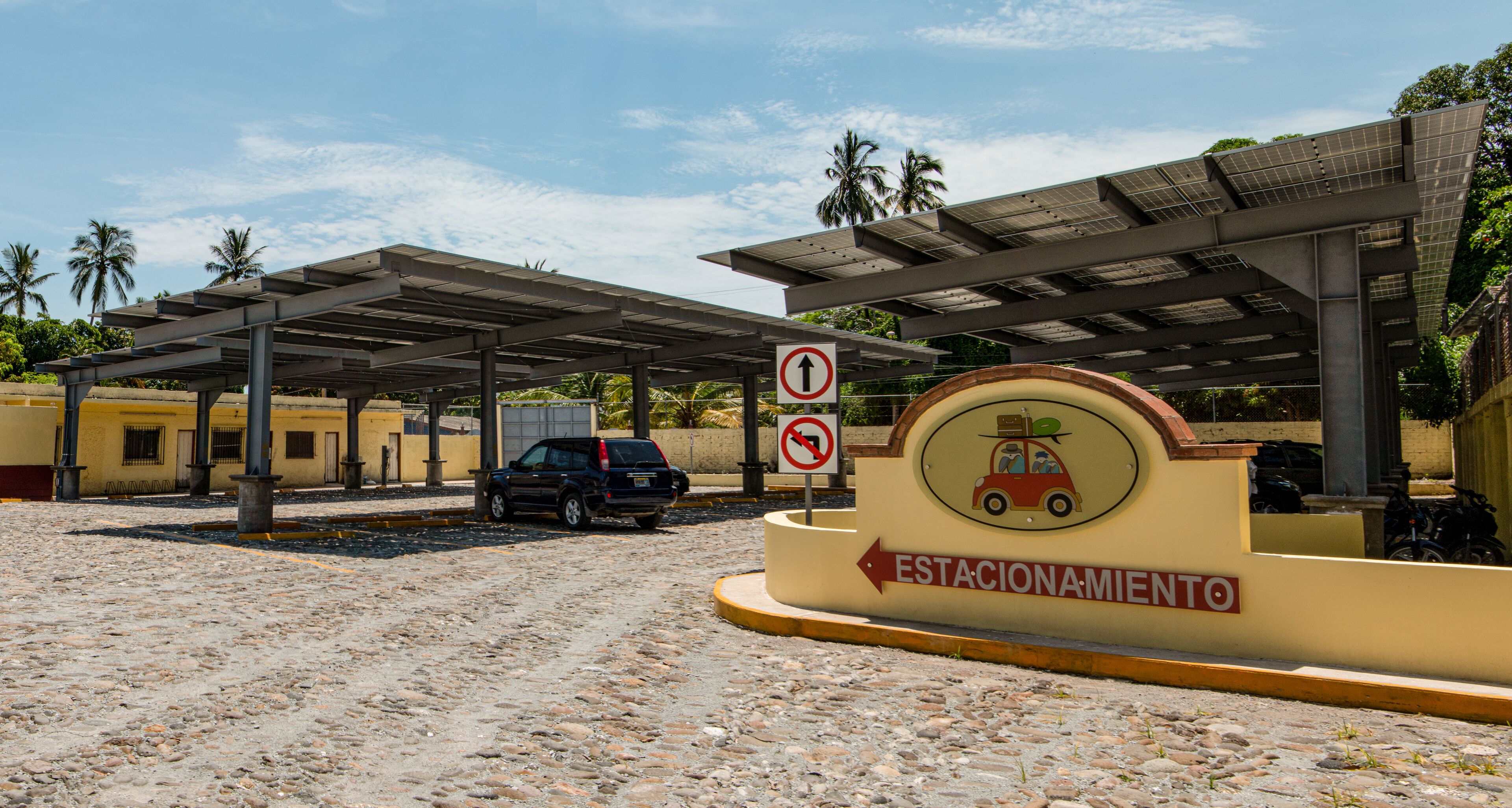 Un área de estacionamiento con un letrero que indica zona prohibida para estacionar y dirección hacia una estación.
