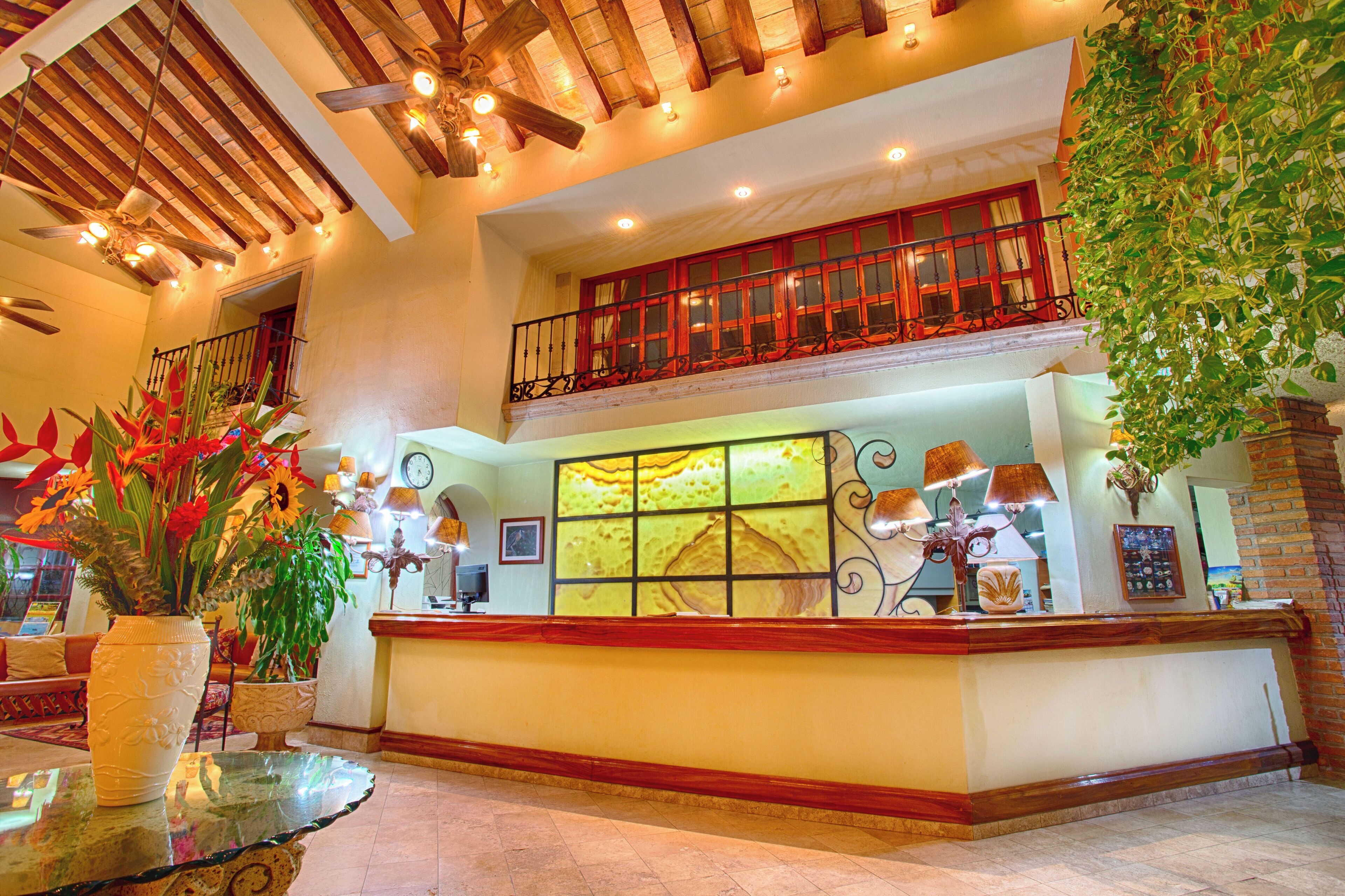 A hotel lobby with a reception desk, a large window with a view, and a ceiling fan.