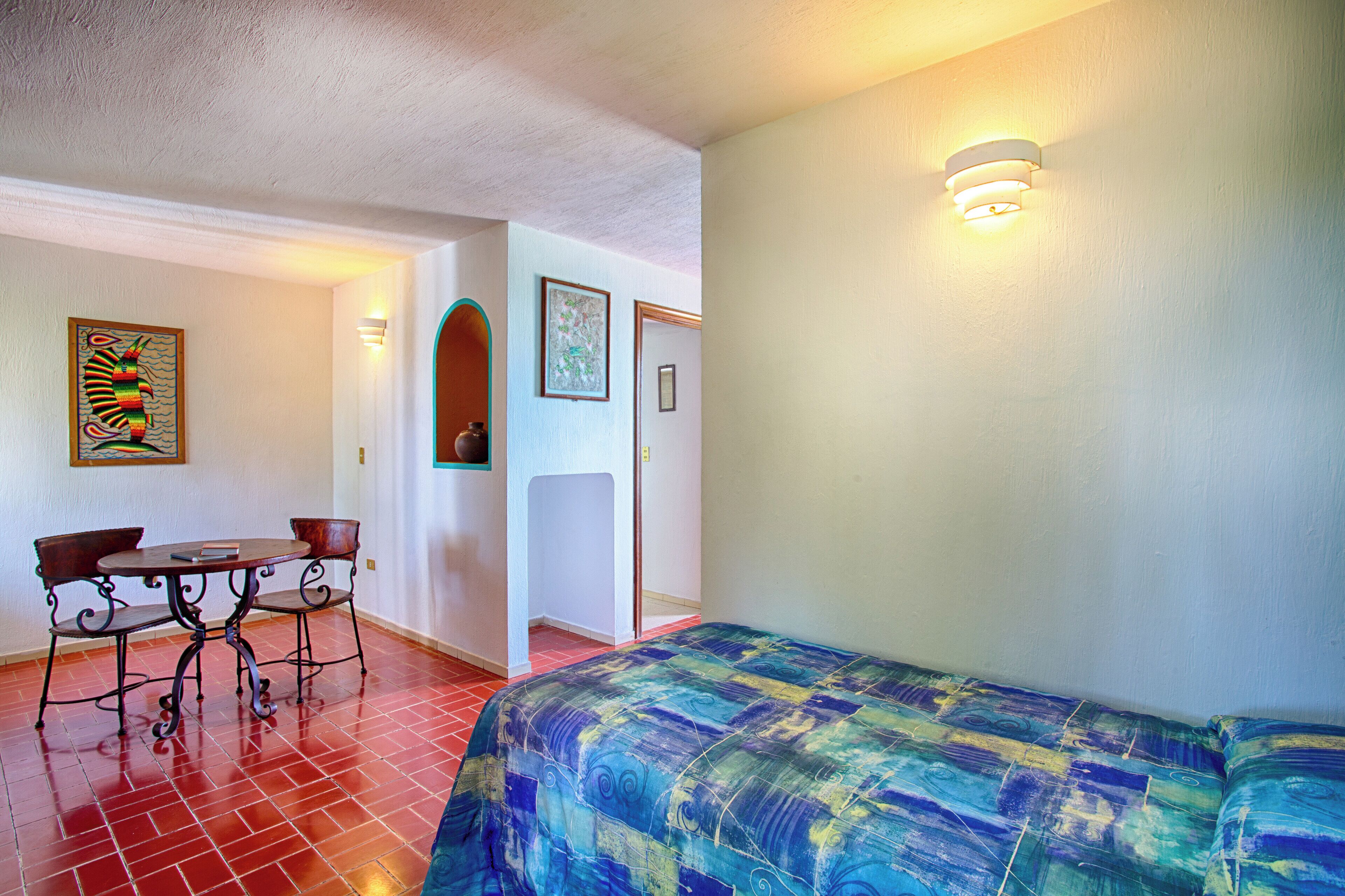 Una habitación con una cama, una mesa y sillas, y una puerta.