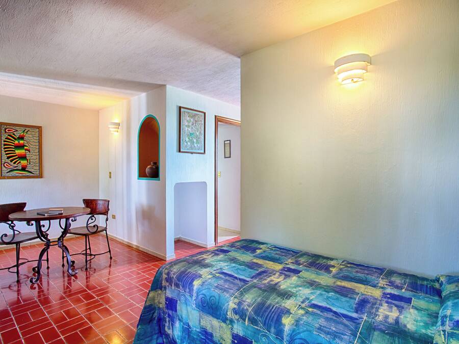 Una habitación con una cama, una mesa y sillas, y una puerta.
