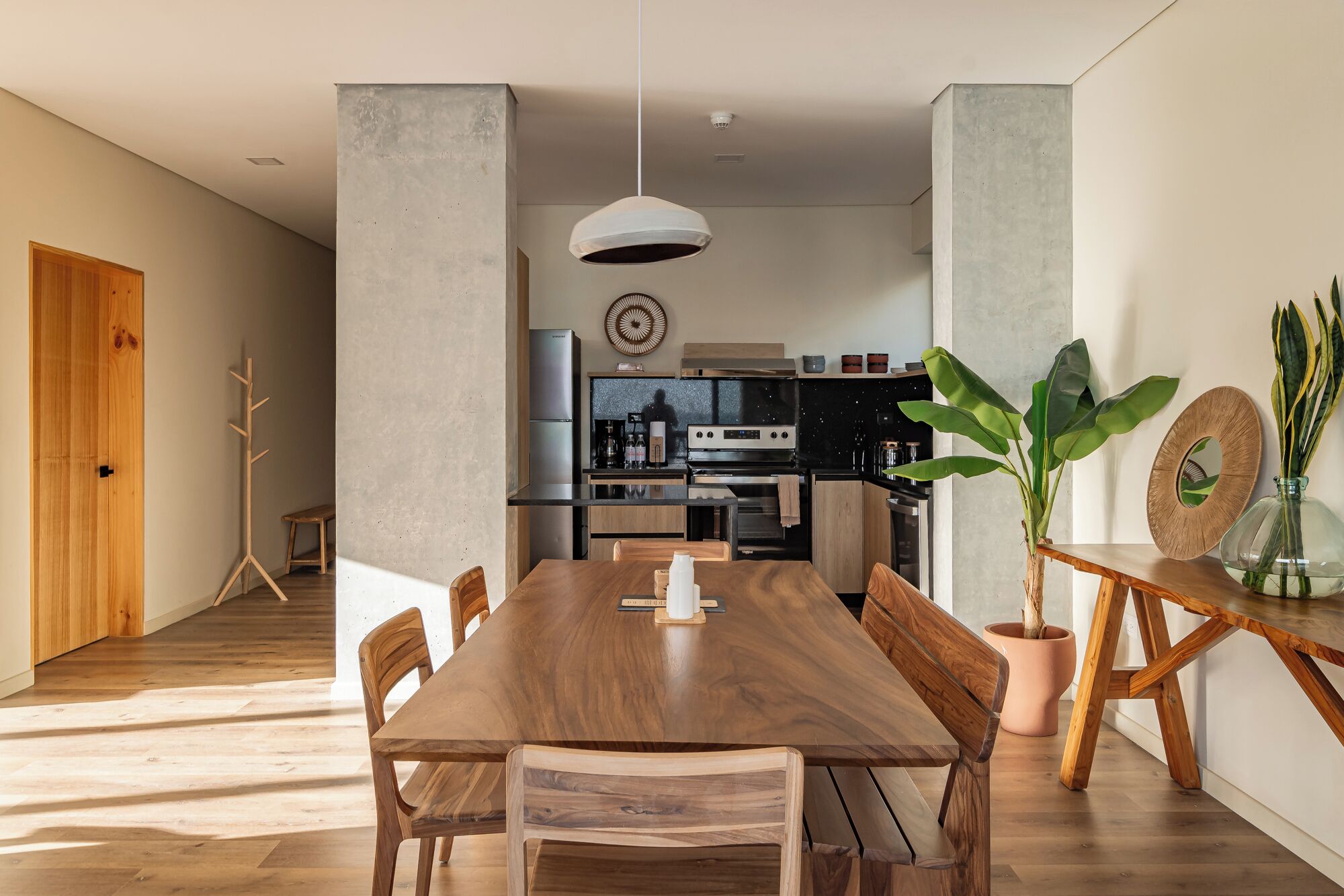 A modern kitchen with a central island, wooden dining table, and chairs.