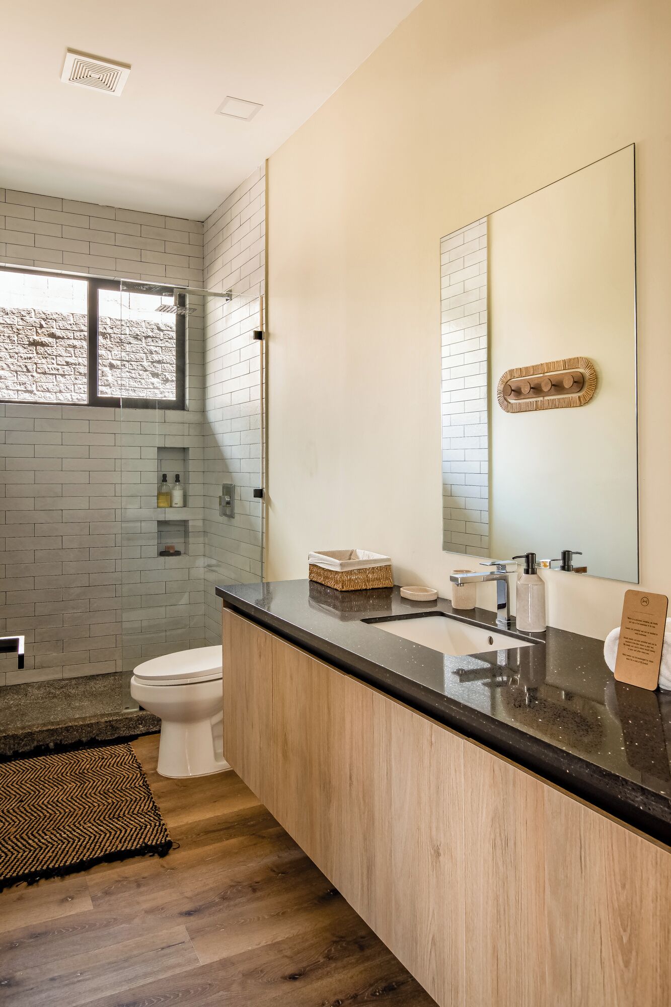 Een moderne badkamer met een grote spiegel, een toilet en een wastafel met een zwart aanrecht.