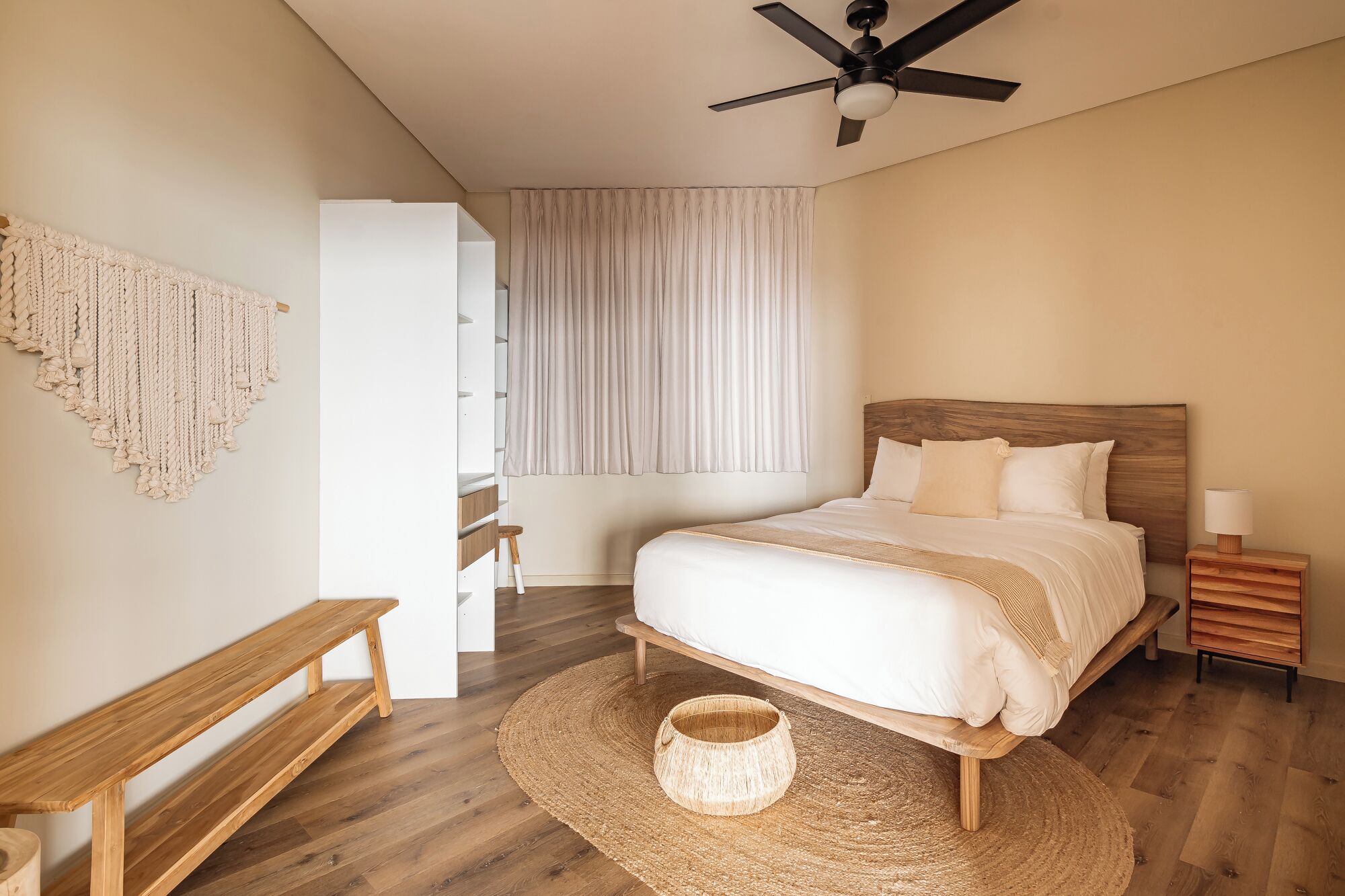 A bedroom with a bed, bedside table, lamp, and a ceiling fan.
