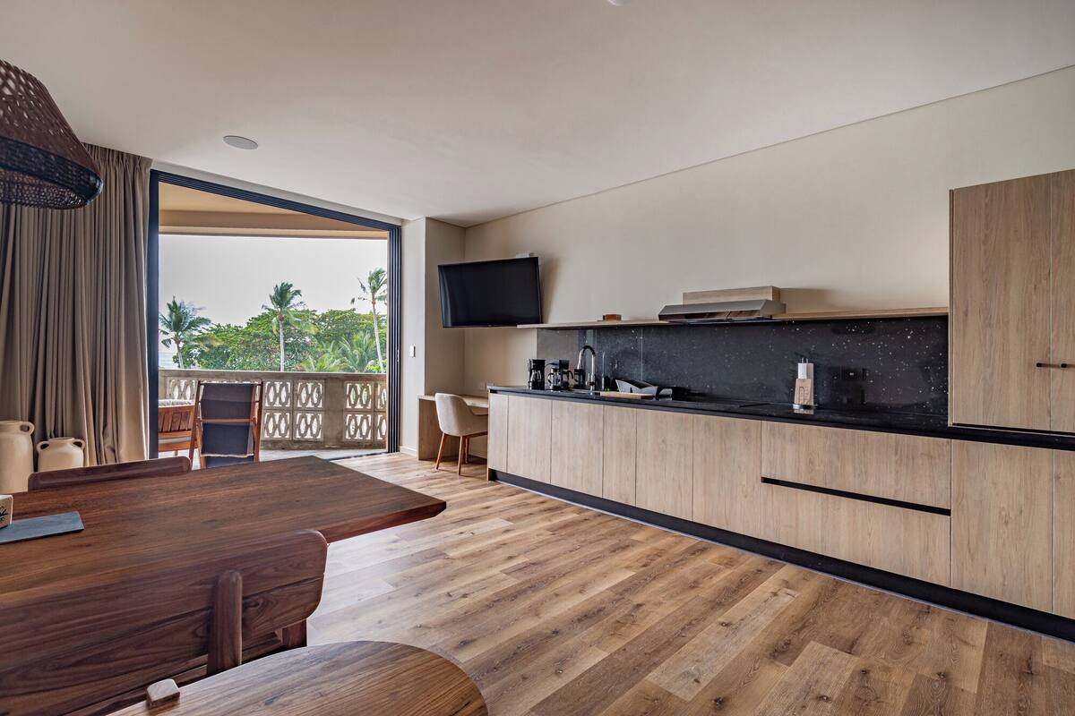 A modern kitchen with a wooden countertop, a built-in oven, and a flat-screen TV mounted above the sink.