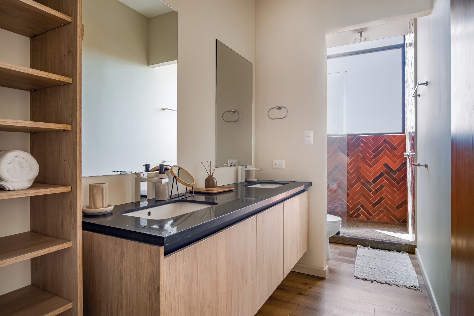 Un baño moderno con tocador de madera, un espejo grande y una zona de ducha con diseño en espiga.