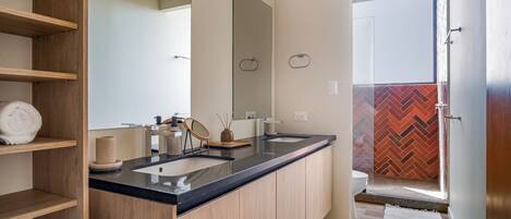 Un baño moderno con tocador de madera, un espejo grande y una zona de ducha con diseño en espiga.