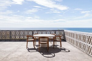 Una terraza con una mesa redonda y cuatro sillas, con vistas a un cuerpo de agua.