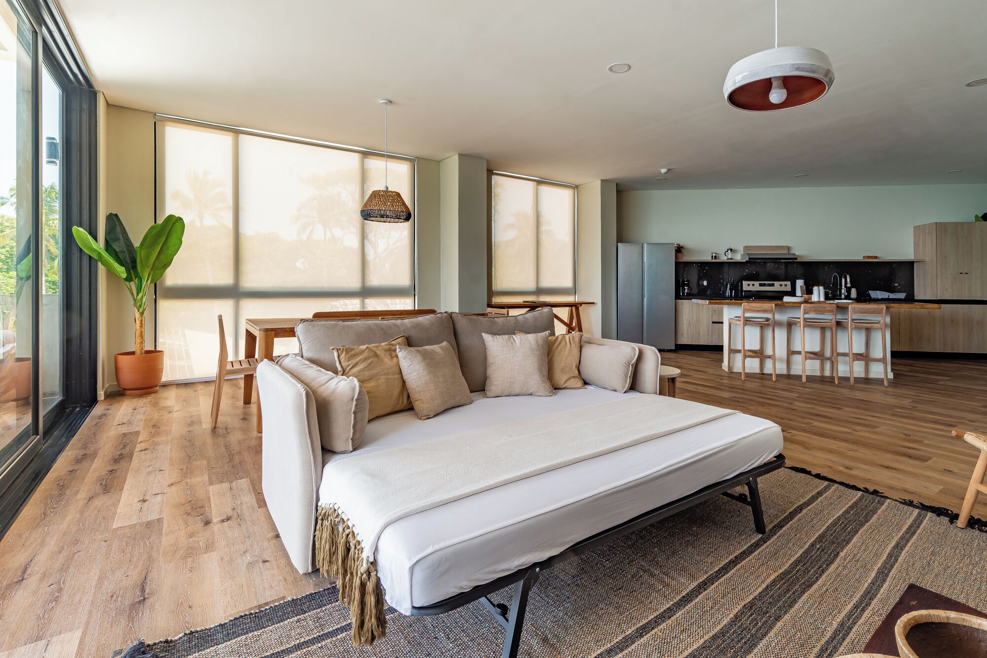 A modern living room with a sofa, a dining area, and a kitchen.