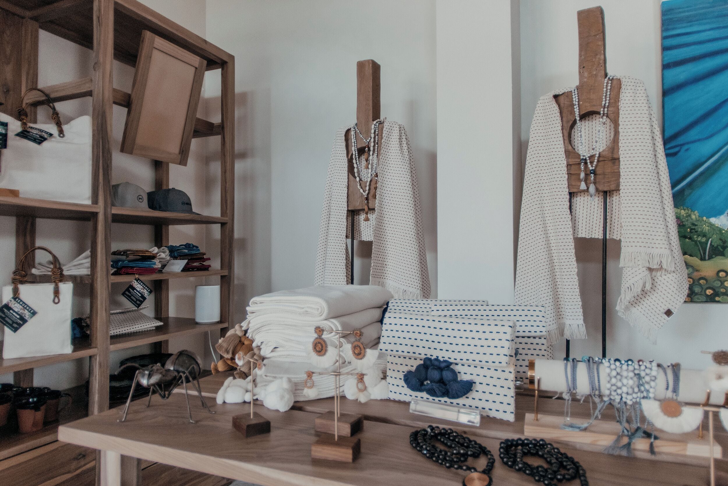 Een boetiek met houten schappen vol handtassen, sieraden en decoratieve stoffen.