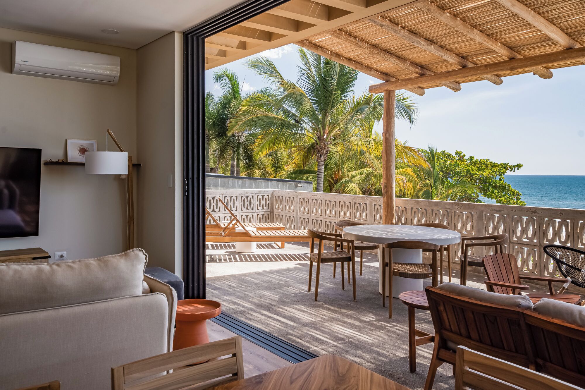 Een balkon met houten meubels, een televisie en uitzicht op de oceaan.