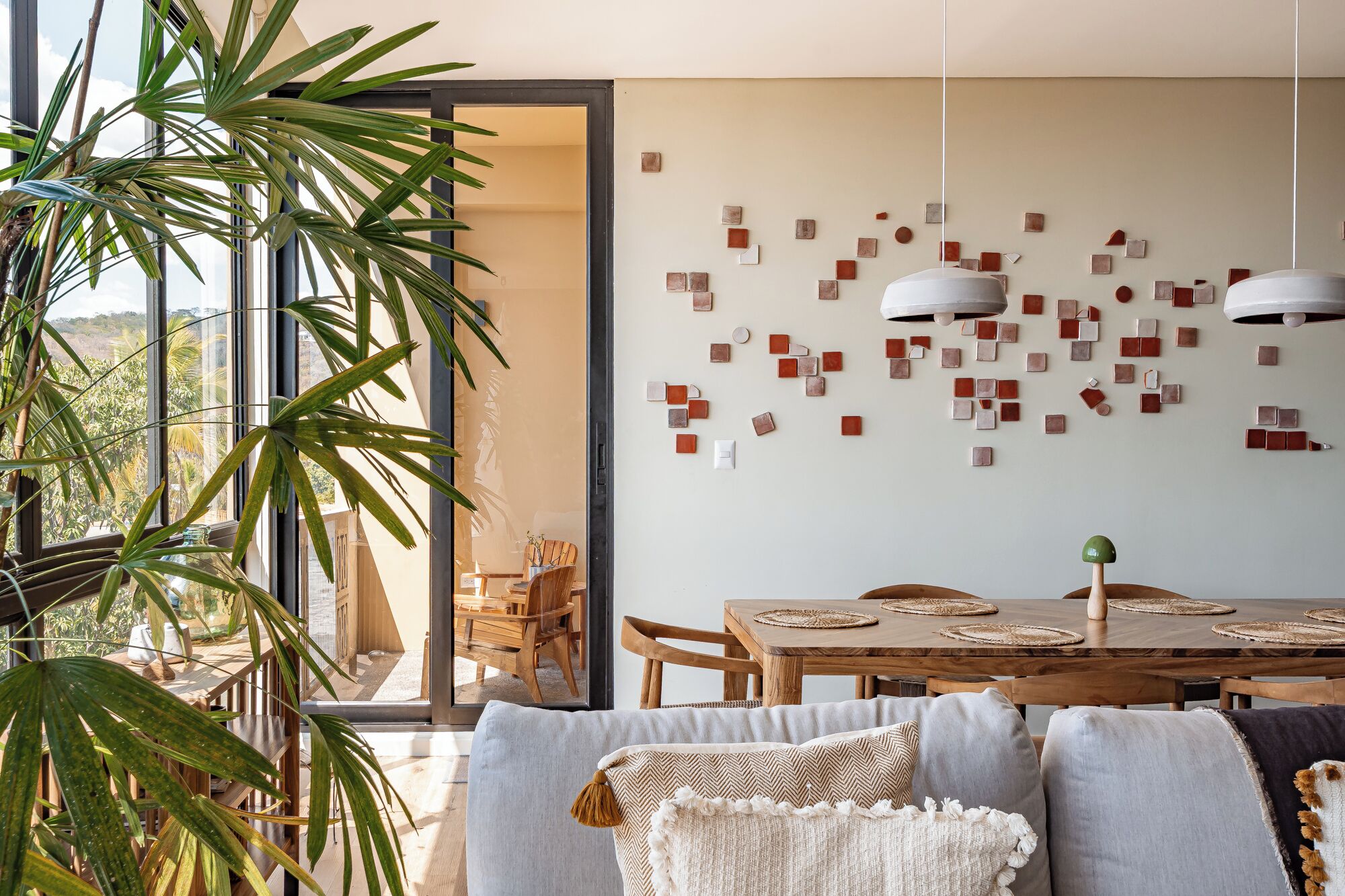 A modern dining area with a wooden table, chairs, and a wall art installation.