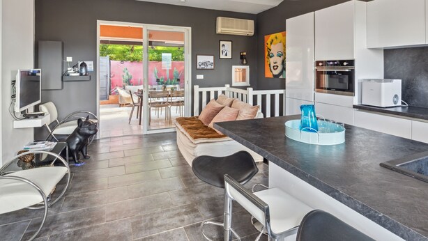 A modern kitchen with white cabinets, a black countertop, and a built-in oven. - Le Mazet aux Cactus - Maison avec piscine partagée (Cogolin)