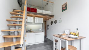 Et moderne køkken med en trætrap, et spiseområde med barstole og et lille bord med mad.