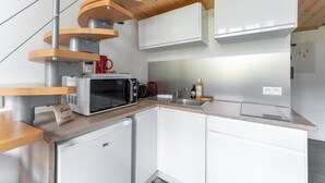 Et moderne køkken med hvide skabe, en mikrobølgeovn, en vask og et træloft.