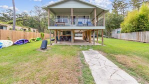 A two-story house with a covered porch, a fenced backyard, and several kayaks. - Relax on the River - Waterfront Property (Maurepas)
