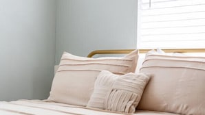 A bed with a wooden frame, beige bedding, and a window with blinds. - Relax on the River - Waterfront Property (Maurepas)