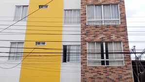 Un edificio de varios pisos con una banda amarilla vertical, fachada de ladrillo y numerosas ventanas.