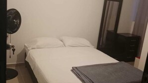Un dormitorio con una cama, una mesita de noche, un espejo y un ventilador.