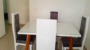 Un comedor con una mesa blanca y cuatro sillas, cada una con pata de madera.